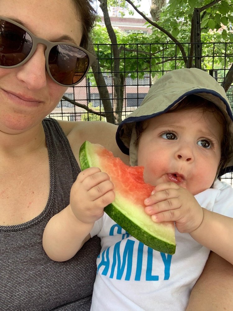 selfie of mother, holding a baby eating watermelon
