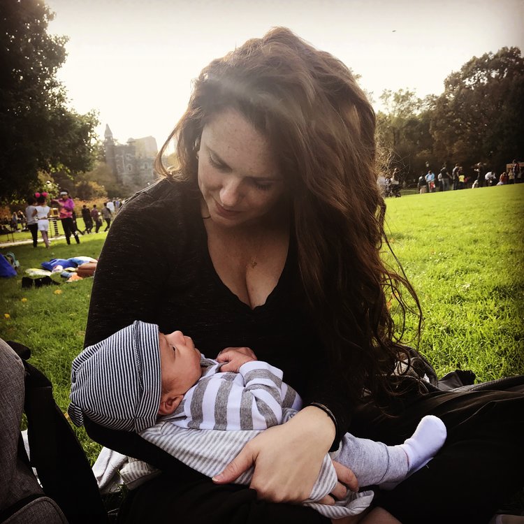 Mother holding baby at a park.